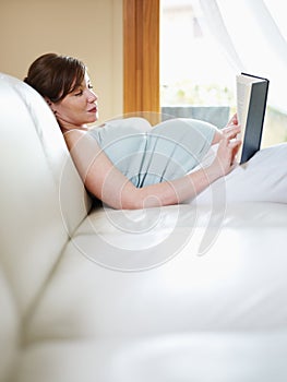 Pregnant woman reading book at home