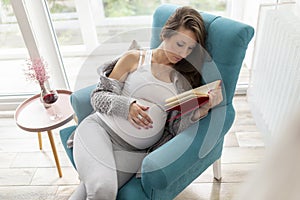 Pregnant woman reading a book at home