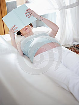 Pregnant woman reading book at home