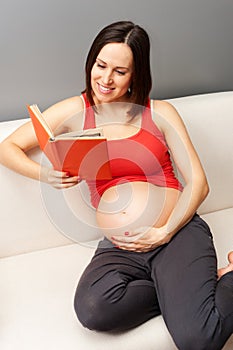 Pregnant woman reading book at home