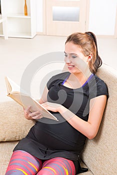 Pregnant woman reading a book at home