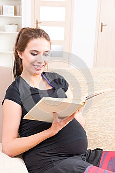 Pregnant woman reading a book at home