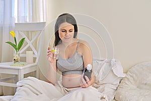 Pregnant woman reading label on bottle with medicine, with vitamins