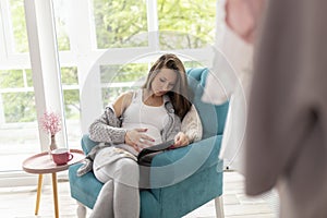 Pregnant woman reading a magazine at home