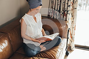 Pregnant woman reading about maternity at home, new mother