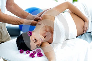 Pregnant woman receiving a back massage from masseur