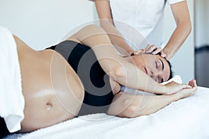 Pregnant woman receiving osteopathic or chiropractic treatment in neck in a clinic photo