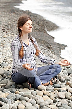 Pregnant woman relax doing yoga on beach