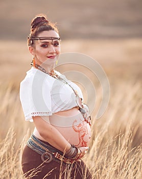 Pregnant woman relaxing in nature on a beautiful sunny day. pregnant woman`s stomach with field in the background