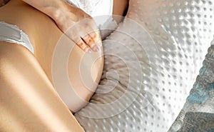 Pregnant woman relaxing or sleeping with belly support pillow in bed