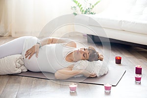 Pregnant woman relaxing after yoga practice in corpse pose at ho