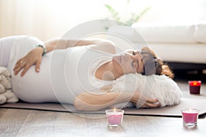 Pregnant woman relaxing after yoga practice in Shavasana pose at photo