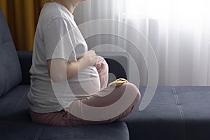 Pregnant woman resting alone at home strokes touches her big belly
