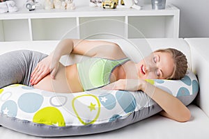 Pregnant woman resting on the couch with pillow