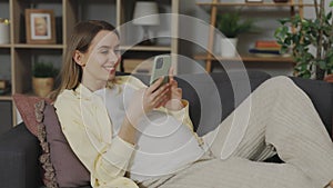 Pregnant woman resting on couch and using smartphone