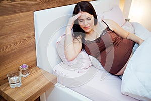 Pregnant woman resting with pills at hand