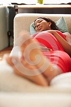 Pregnant Woman Resting On Sofa At Home