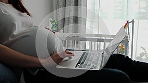 Pregnant Woman Resting on a Sofa at Home and Working Remotely with Laptop Computer Using Online Technology.