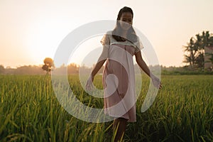 Pregnant woman in rice field on sunset day
