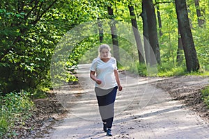 Pregnant woman running outdoors in the park or forest. Activity and sport during pregnancy. Healthy lifestyle