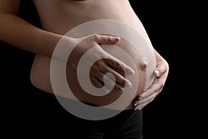 Pregnant woman's abdomen against black background