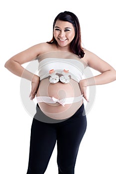 Pregnant woman`s belly with baby shoes and ribbon bow