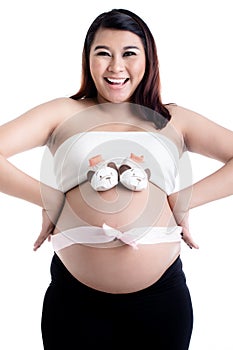 Pregnant woman`s belly with baby shoes and ribbon bow