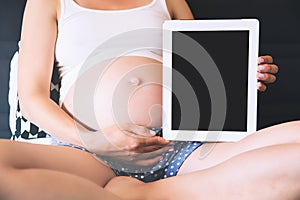 Pregnant woman showing blank digital tablet screen