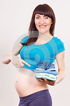 Pregnant woman showing clothing for newborn, expecting for baby