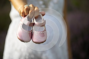 Pregnant woman showing pink baby shoes in the foreground