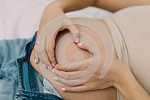 Pregnant woman shows Heart on her Big Belly. Pregnancy Concept. Pregnant Woman. Young Mother.