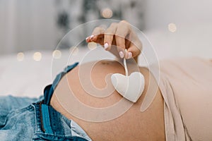 Pregnant woman shows Heart on her Big Belly. Pregnancy Concept. Pregnant Woman. Young Mother.