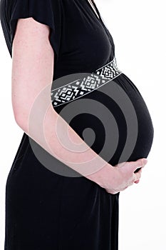 Pregnant woman side profile belly in dress black view in white background holding tummy under hands in studio