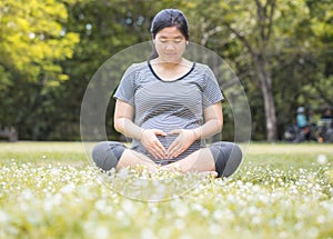 Pregnant woman sit on the ground carry her belly with love sign.