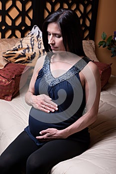 Pregnant Woman Sits on Bed