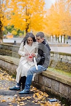 A pregnant woman sits on her husband's lap and holds small baby socks in her hands.