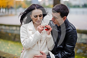 A pregnant woman sits on her husband's lap and holds small baby socks in her hands.