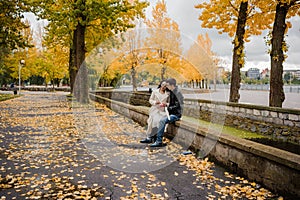 A pregnant woman sits on her husband's lap and holds small baby socks in her hands.