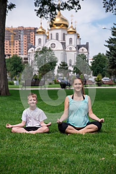 Pregnant woman sits in yoga posies and meditates with her son photo
