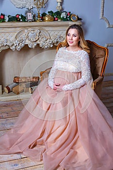 A pregnant woman sitting in a beautiful dress on the couch. the concept of motherhood