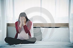 Pregnant woman sitting on bed and feeling upset and sad from family conflict problem