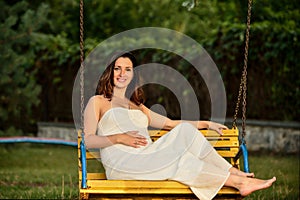 Pregnant woman sitting on a bench warm weather