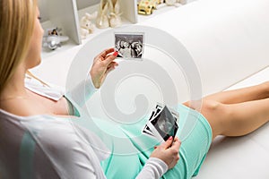 Pregnant woman sitting on couch and looking at sonography