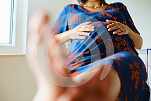 Pregnant Woman Sitting With Feet Up And Touching Stomach