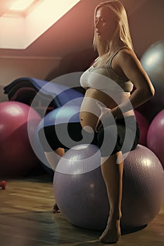 Pregnant woman sitting on fit ball in gym. Motherhood and maternity concept Pregnancy and fertility