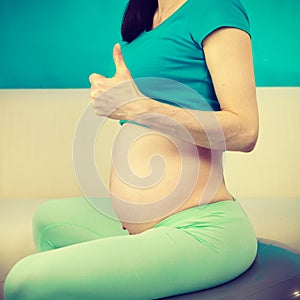 Pregnant woman sitting on fit ball, thumb up gesture