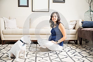 Pregnant Woman Sitting On Floor With Crossed Legs By Dog