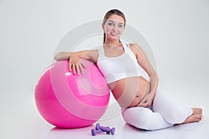 Pregnant woman sitting on the floor with fitness ball