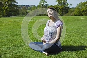 Pregnant Woman Sitting On Grass