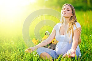 Pregnant woman sitting on green field